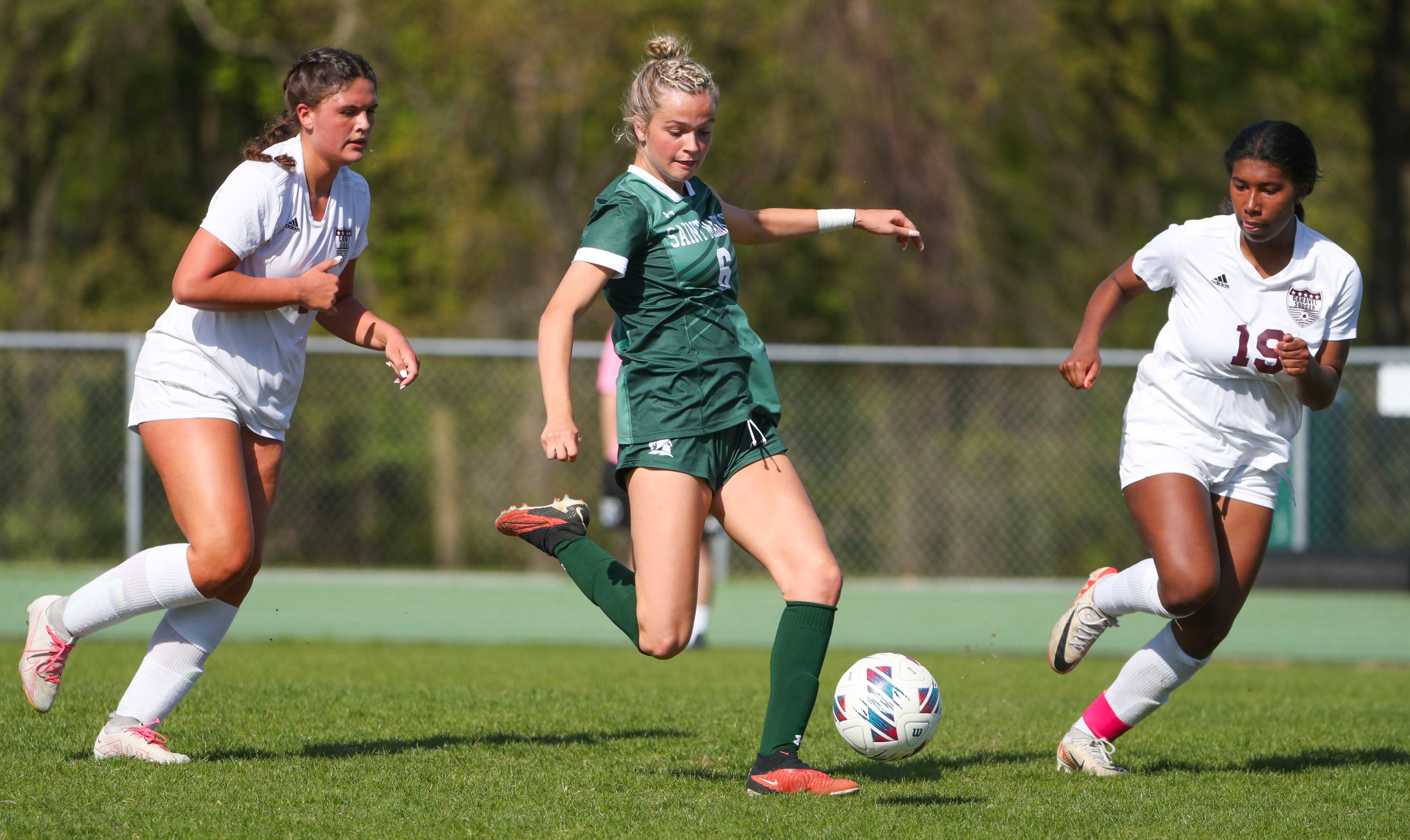 Caravel's Reese Mushinski (left) and Maci Hood coverage on Saint Mark's Lily Phillips in the first half of the Bucs' 1-0 overtime win at Saint Mark's High School, Wednesday, April 24, 2024.